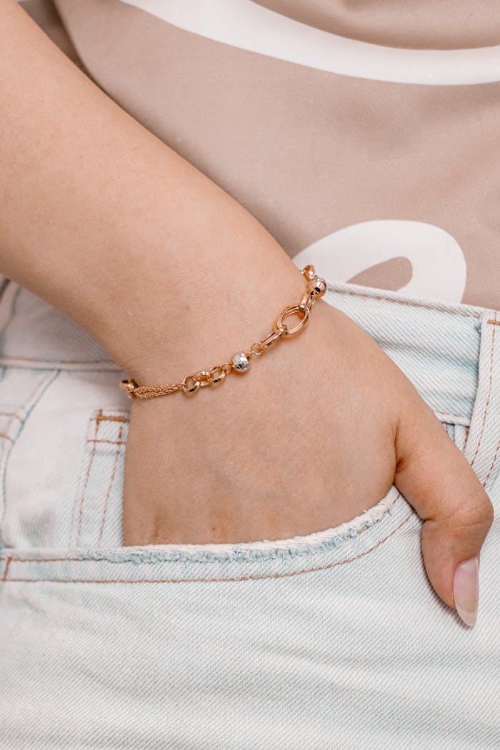 Close-up of a gold bracelet on a wrist against denim for a chic fashion statement.